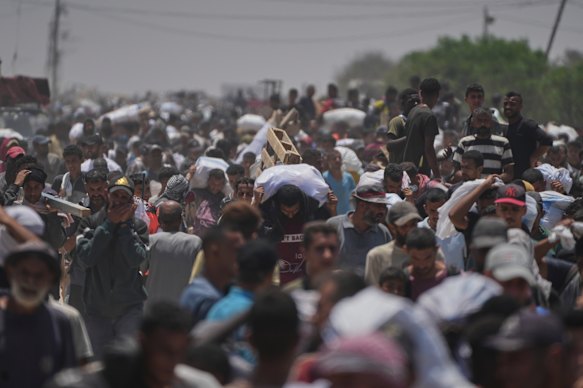Palestinians carry bags containing food and humanitarian aid packages delivered by the Gaza Humanitarian Foundation in Rafah.