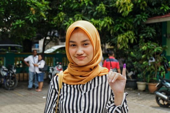 Putri Elma, votante por primera vez, muestra el dedo entintado que demuestra que ya ha emitido su voto.