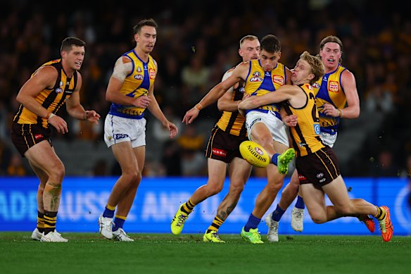 Elijah Hewett kicks the ball under pressure during clash between Hawthorn and West Coast at Marvel Stadium on Sunday.