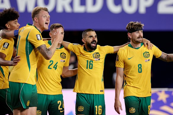 Aziz Behich (centre) celebrates Australia’s draw with Paraguay.