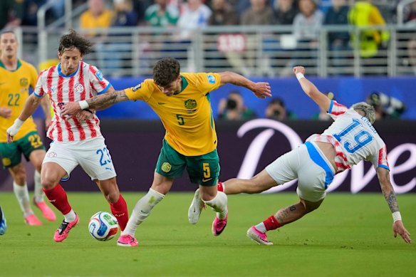 Jordan Bos battles for the ball with Paraguay’s Matias Galarza and Julio Enciso.