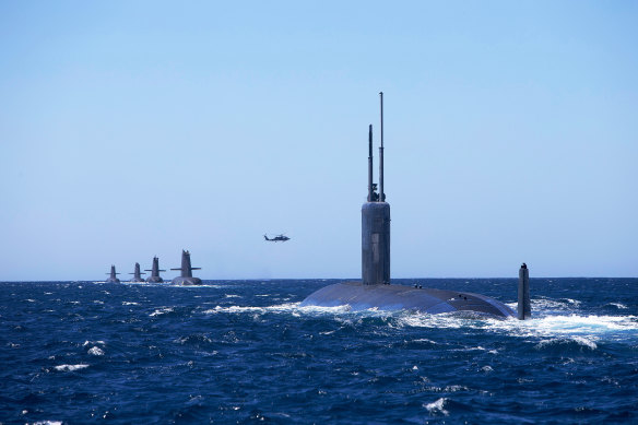 US Navy submarine USS Santa Fe joins Royal Australian Navy Collins-class submarines in formation, as an MH-60R Seahawk flies overhead in the West Australian Exercise Area.