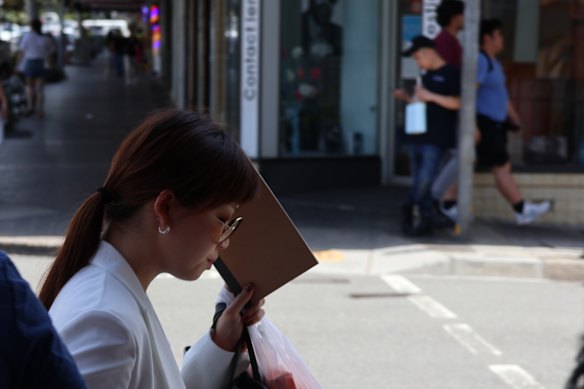 Andrew W Hu’s girlfriend, Cheryl Tan, tries to shield her face last month.