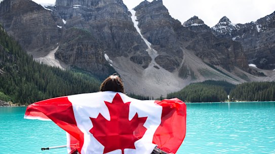 A young girl in a canoe holding a Canadian flag in Lake Moraine, in Banff National Park, Alberta, Canada.