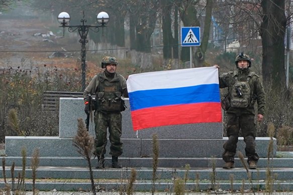 Russian soldiers hold a Russian national flag in Pokrovsk, an image taken from video provided by Russian Defence Ministry Press Service on Tuesday.