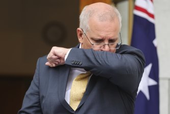 Le Premier ministre Scott Morrison tousse lors d'une conférence de presse au Parlement à Canberra, quelques heures avant d'être testé positif au COVID-19.