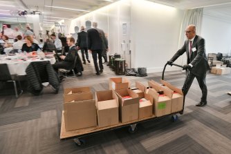 Un membre du personnel de la trésorerie et des finances avec une charge de chariot de documents budgétaires.