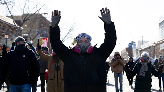 Protesters advance towardsfederal agents with their hands up near the site of the fatal shooting of Alex Pretti.