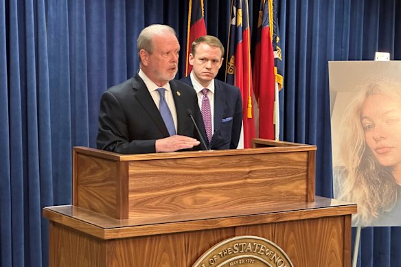 North Carolina state Senate leader Phil Berger speaks at a press conference while House Speaker Destin Hall listens and stands next to a photo of commuter train stabbing victim Iryna Zarutska.