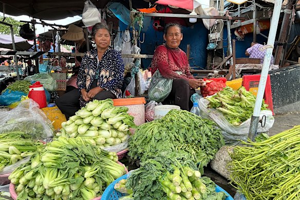 Um Pov (left) had not sold any vegetables by late morning.