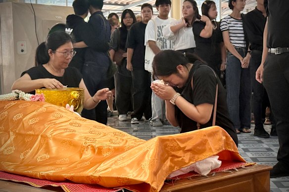 A mourner prays and weeps over the body of teacher Nanchanatporn Nakplang. 