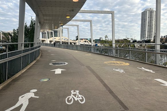 Signs indicating the previous 10km/h speed limit on the Kurilpa Bridge have been painted over on the concrete, but the black markings have worn down.