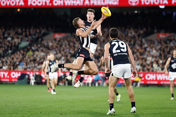 Harry Perryman of the Magpies marks the ball ahead of Sam Walsh of the Blues.
