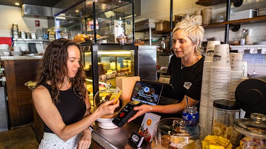 Expresso co-owner Jessica Kotzen, receives payment from customer Amber Boardman at her cafe in Brookvale, Sydney.