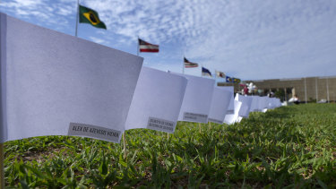 The names of people who died of COVID-19 cover white flags in a field as part of a protest against the government’s health policies outside the National Congress in Brasilia, Brazil.
