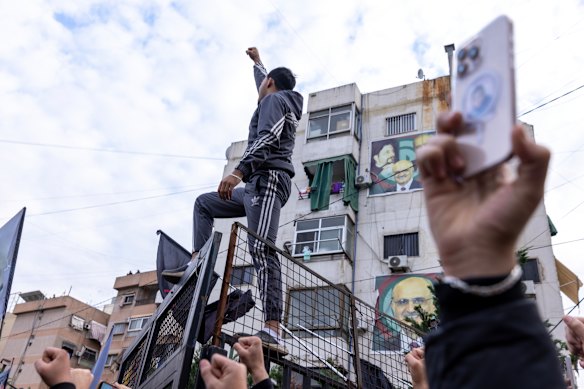  A man on a fence with raises his clenched fist while people chant “Death to America” at Ashoura Square in southern Beirut, on Sunday. Hezbollah called the demonstration following the death of Iran’s former Supreme Leader, Ayatollah Ali Khamenei.