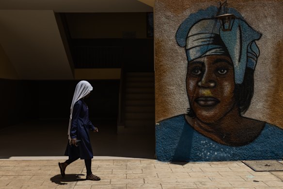 A student walks past a wall painting of Mariama Ba at the Mariama Ba school in Goree Island, Senegal.