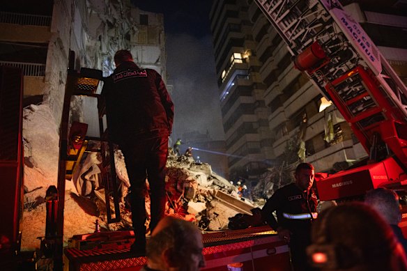 A first responder with the Internal Security Forces stands on a firetruck while rescue workers search the rubble for survivors and casualties after an Israeli attack targeted a residential building in Beirut.