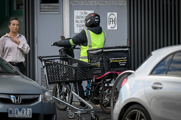 A food delivery e-bike rider rides on the footpath on Glenferrie Road, Hawthorn