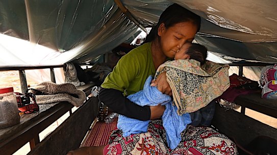 Hong Srey Rith holds her eight-day-old baby, Lin Kakada, in their shelter at the Batthkav primary school. Srey Rith went into labour as she fled her home.