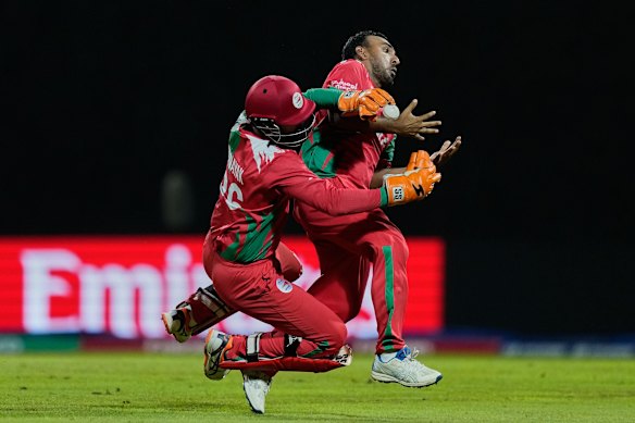 Oman’s Vinayak Shukla and Shakeel Ahamed collide while taking the catch of Australia’s Travis Head.