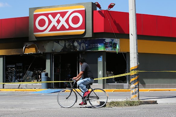 A man cycles past a burnt-out shop in San Francisco del Ricon in Guanajuato state.