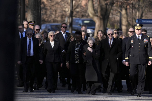 Jimmy Carter’s sons, Chip (left) and Jack (second from right), their family and others escort the former president’s coffin in Atlanta.