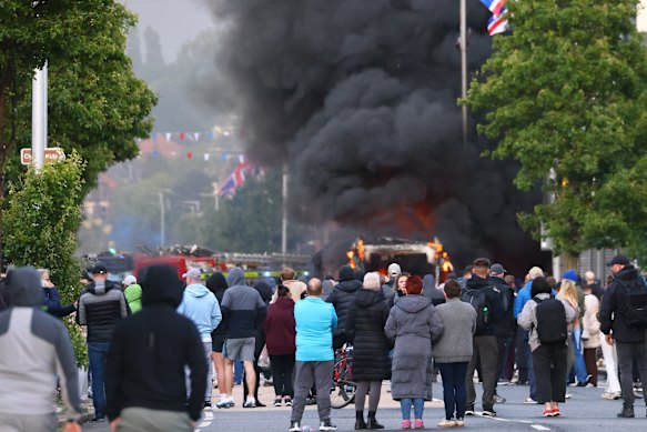 People watch as the vehicle burns in North Belfast.