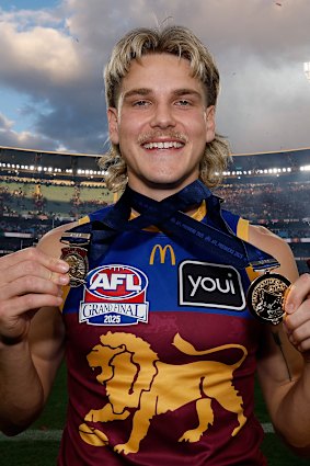 Father-son Lion Will Ashcroft holds his Norm Smith Medal and his premiership medal after the 2025 flag win.