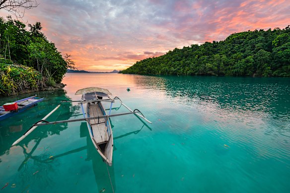 A traditional boat floating on a scenic blue lagoon in the Togean (or Togian) Islands, Central Sulawesi. 