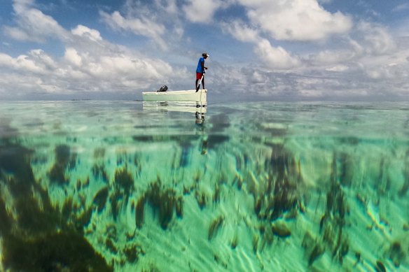 A man stands on a boat over a coral reef in the Dutch Cays of Guna Yala on Panama’s Caribbean coast.
