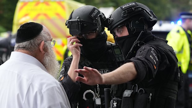 Members of the public and congregants seen as police and other emergency responders attend the Heaton Park Hebrew Congregation Synagogue.