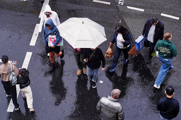 People walk through the city with umbrellas on Sunday as rain hits Melbourne.