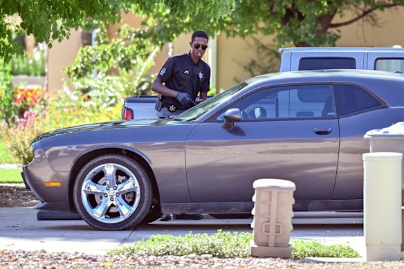 A law enforcement official examines a silver Dodge car outside the family home of Tyler Robinson, the man accused of assassinating Kirk.