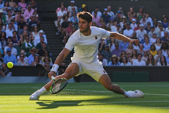 Defending two-time Wimbledon champion Carlos Alcaraz slides to return serve against Cameron Norrie.