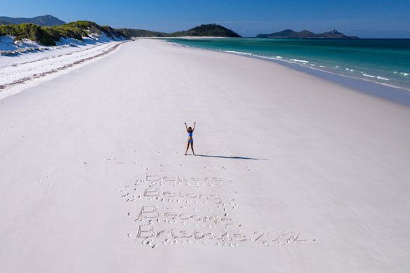 “Believe. Belong. Become. Brisbane 2032.” written in the sand in the Whitsundays.