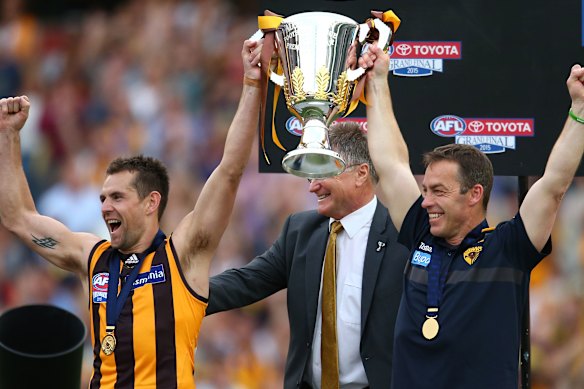 Clarkson (right) and then Hawthorn skipper Luke Hodge hold the 2015 premiership cup aloft. Clarkson coached the Hawks to four flags.
