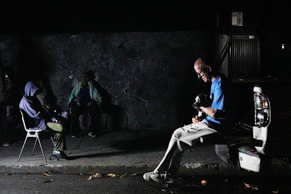 A man sits with his dog outside their home following the quakes.