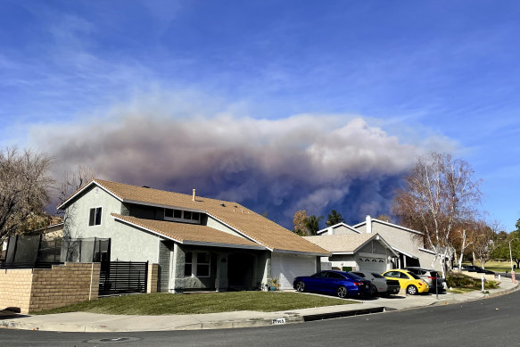 A large plume of smoke caused by the Hughes Fire rises from Castaic Lake, as seen from a neighbourhood of Santa Clarita, California.