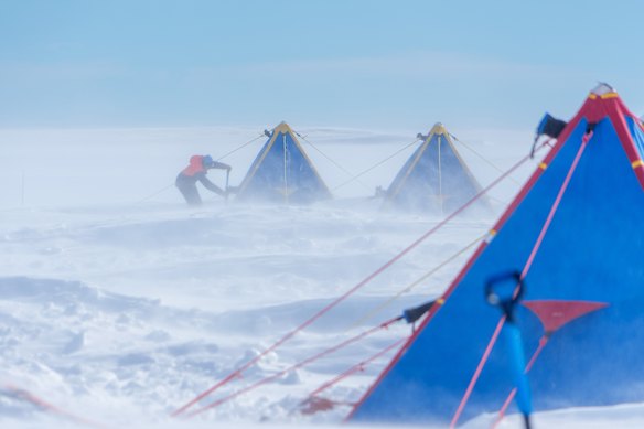 Dr Yixi Zheng of the British Antarctic Survey removes snow from her tent on the Thwaites Glacier in January 2026.