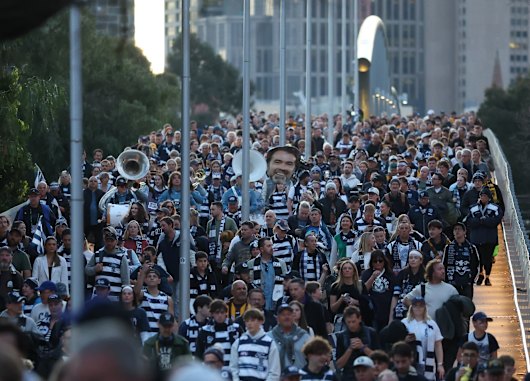 A sea of blue and white crosses the footbridge to the MCG.
