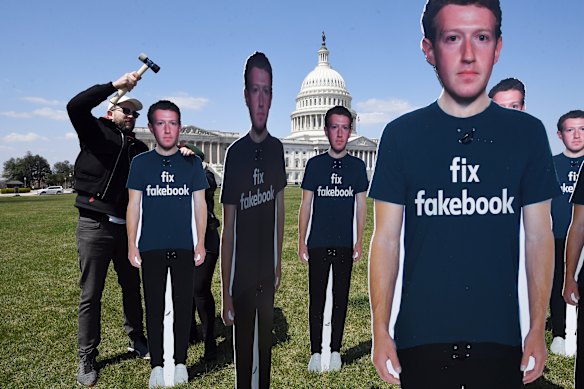 An activist helps place Zuckerberg cut-outs outside the US Capitol in April 2018 as the Facebook founder prepared to appear before Congress.