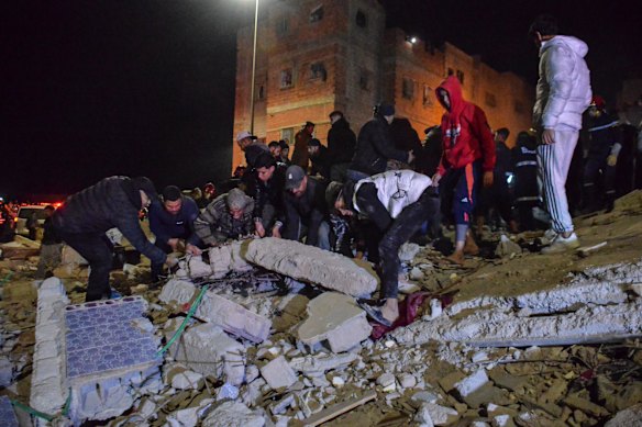 Rescue workers and residents search for survivors amid the wreckage of two collapsed buildings.