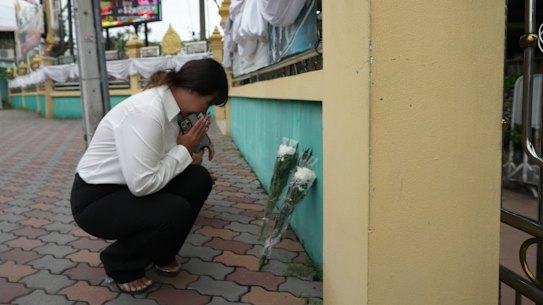 A woman lays flowers and offers prayers at Debsirin Nonthaburi School on Saturday.