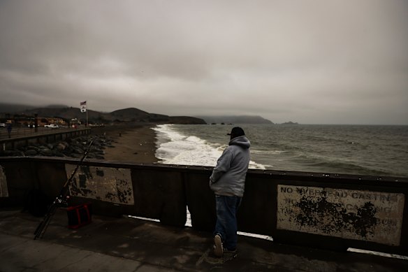 A fisherman looks out at the beach where a tsunami advisory was in effect in Pacifica, California.