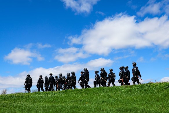 Law enforcement in riot gear walk in a field after animal welfare activists attempted to gain entry to Ridglan Farms beagle breeding and research facility in Blue Mounds, Wisconsin.