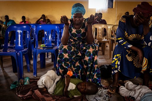 At an information session for parents with children living with disability, 44-year-old mother Winifred Achan prays for her 12-year-old son Shedrac Ogwakol.