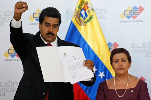 Maduro raises his fist as he holds up the official certificate declaring him winner of the presidential election in 2013.