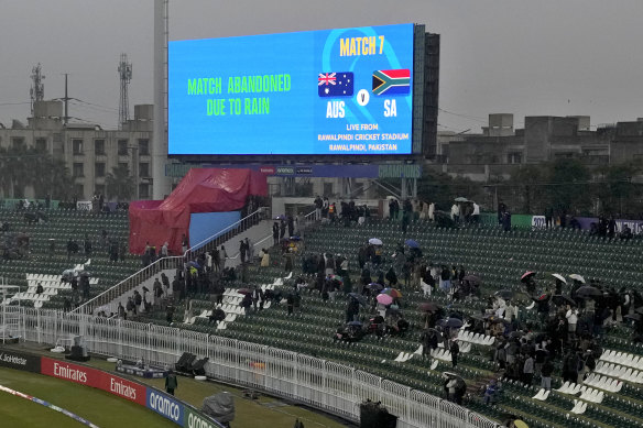 Fans look at the big screen showing the message that the ICC Champions Trophy cricket match between Australia and South Africa is abandoned due to rain.