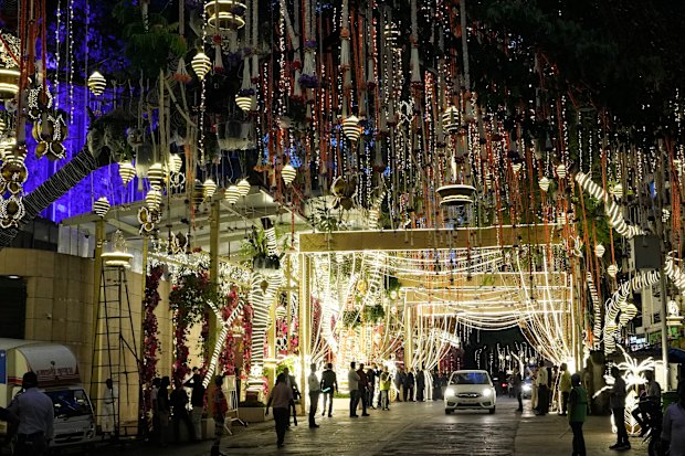 People walk past the Antilia mansion in Mumbai, house of billionaire Mukesh Ambani, lit up for the wedding of his son Anant Ambani and Radhika Merchant.
